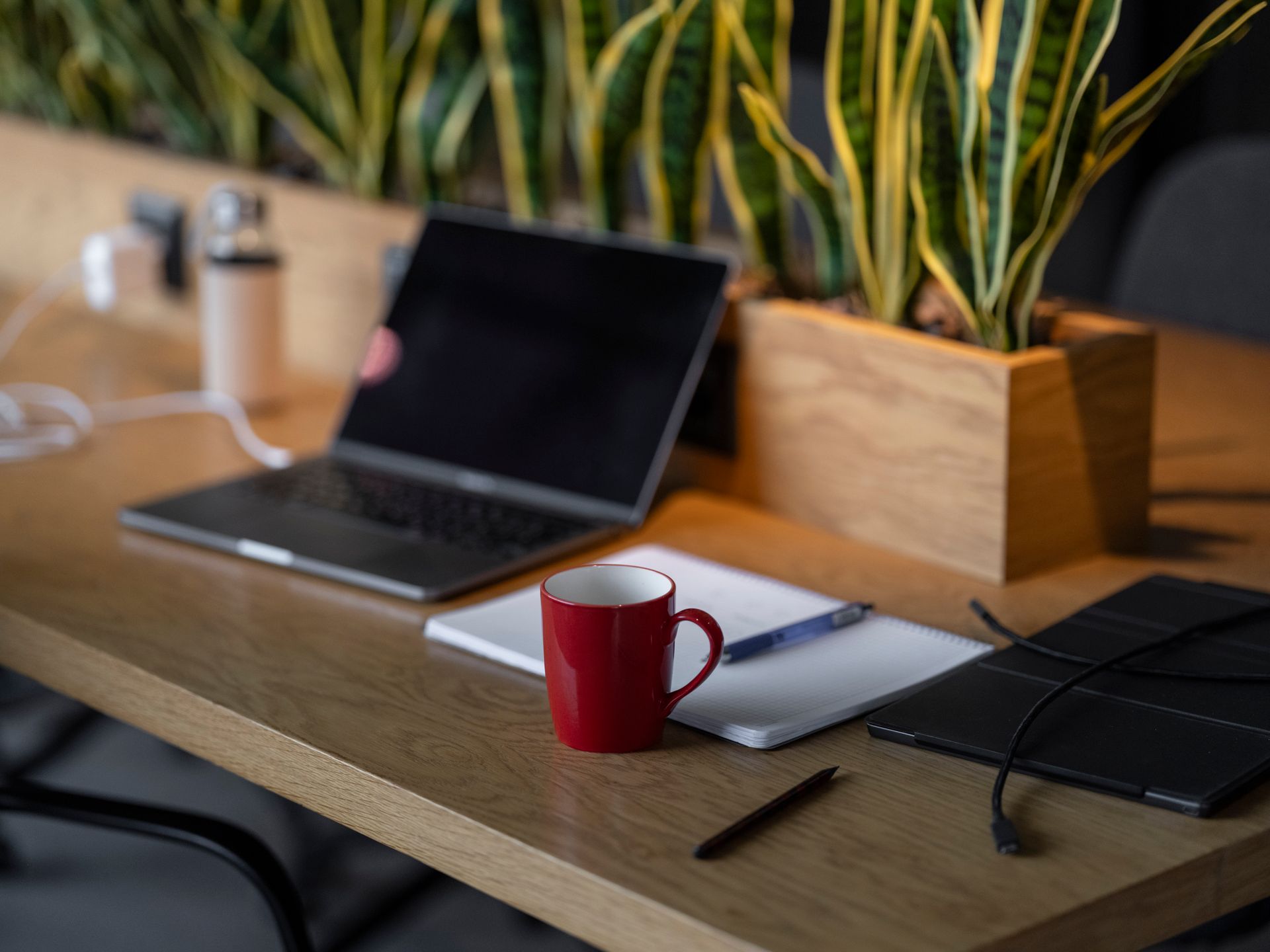 Cozy workspace setup with laptop, notebook, and coffee mug on a wooden table
