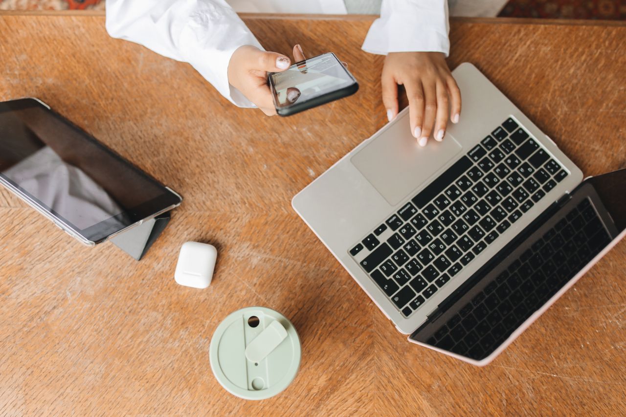 Professional in white dress shirt using a laptop at desk in a modern office setting